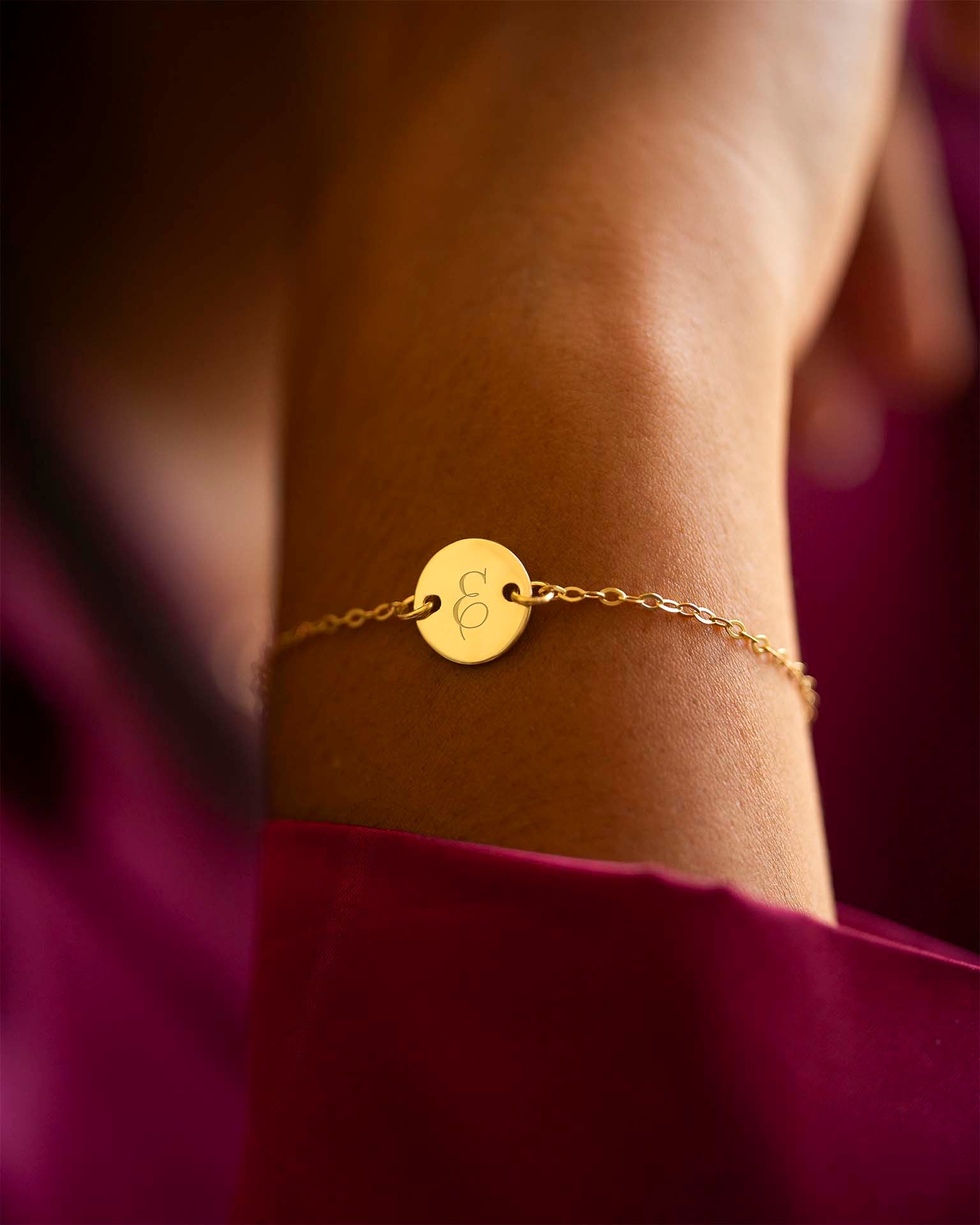 Gold bracelet with a circular tag on a wrist against a blurred background | Christmas
