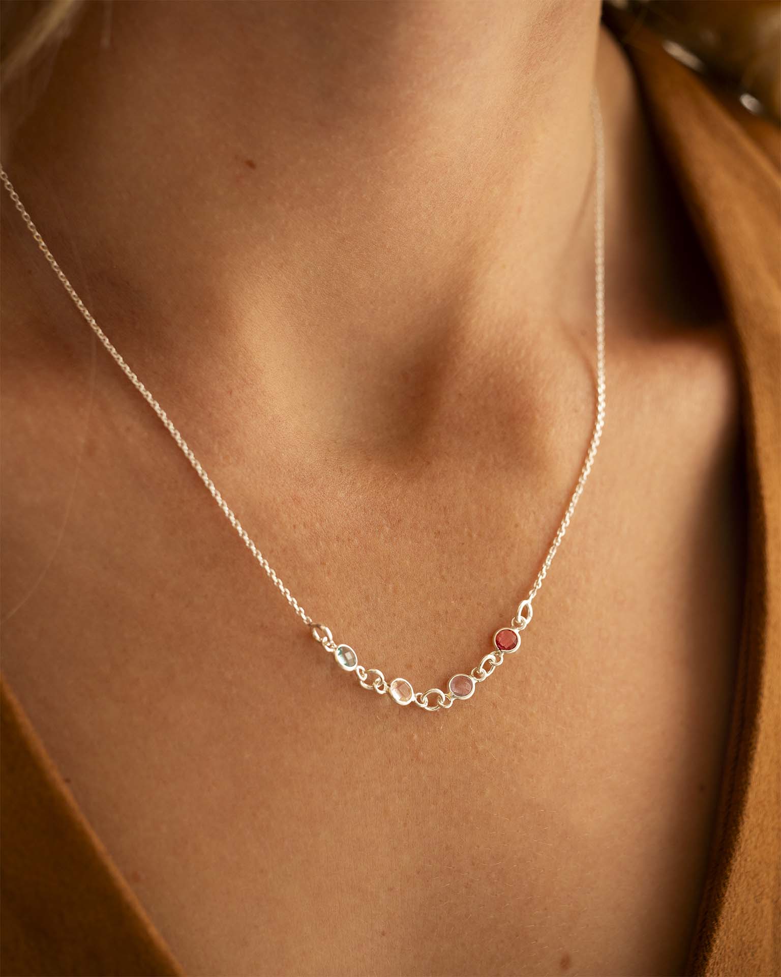 Silver necklace with small round pendants on a person wearing a brown garment. | Christmas