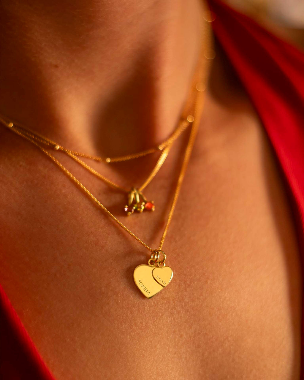 Close-up of a person wearing gold necklaces with heart pendants. | Christmas