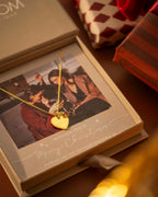 Gold heart-shaped necklace in a Christmas gift box with a photo of a couple | Christmas