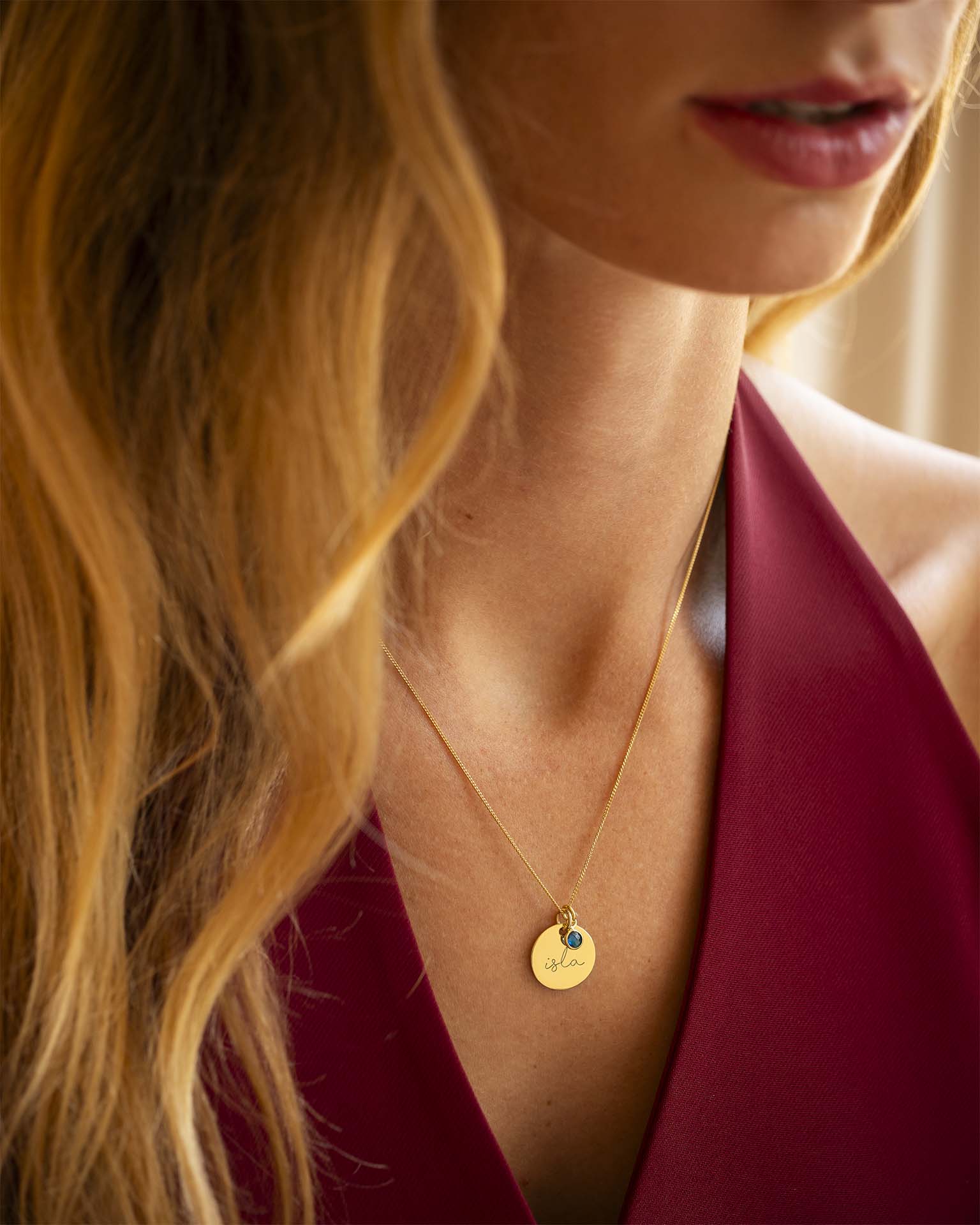 Close-up of a woman wearing a gold necklace with a pendant.