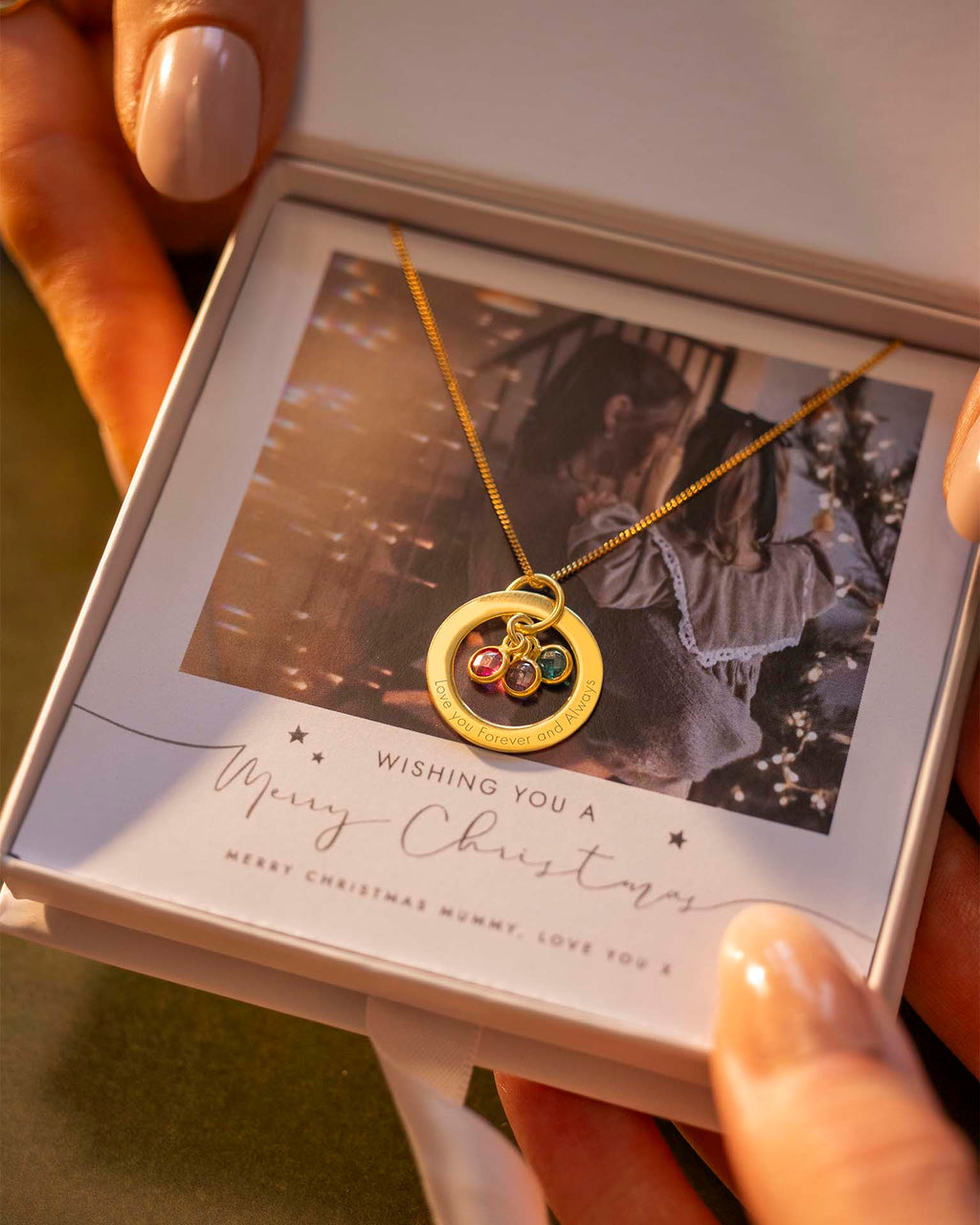 Gold necklace with a pendant in a decorative box, held by a hand.