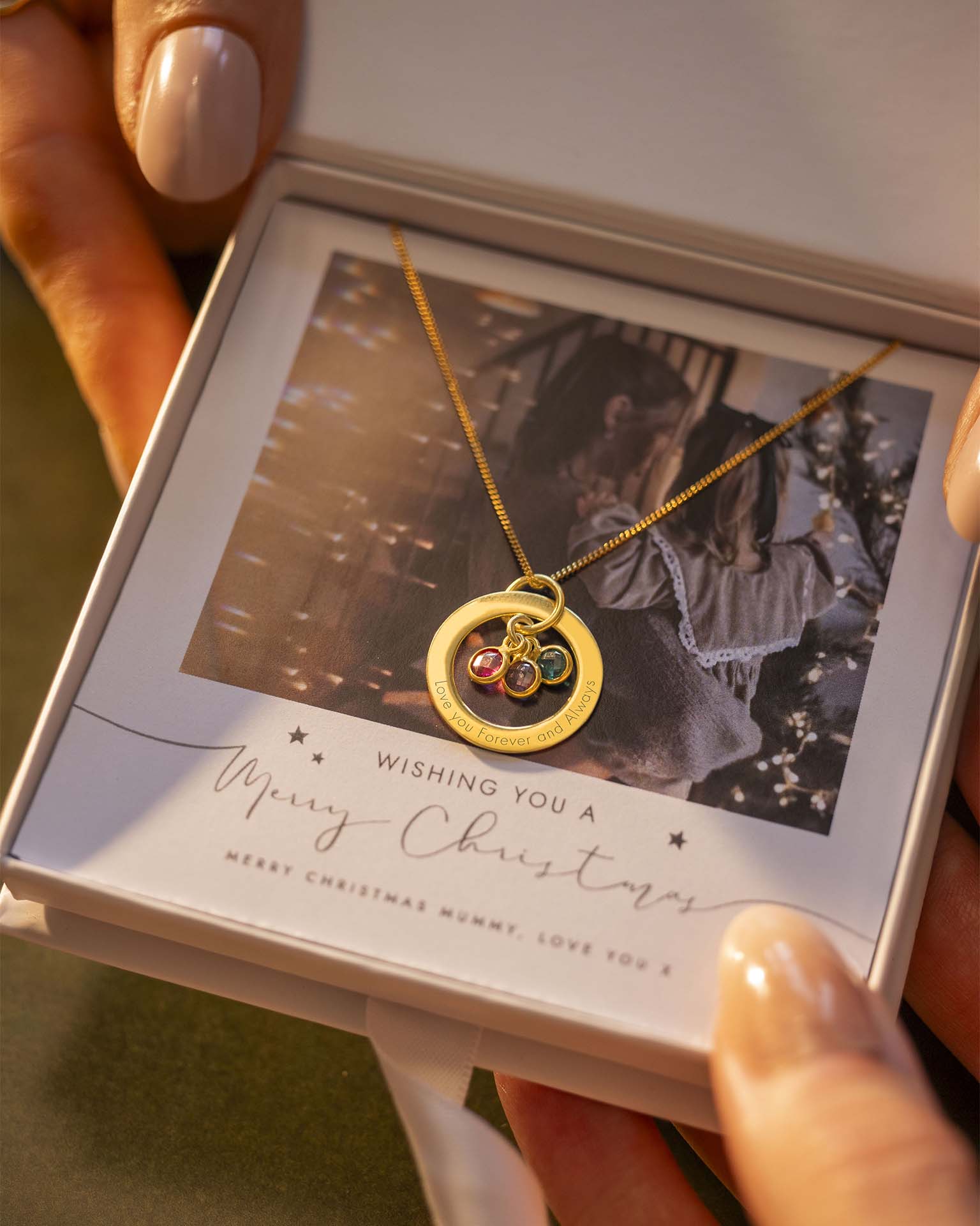Gold necklace with a pendant in a decorative box, held by a hand.