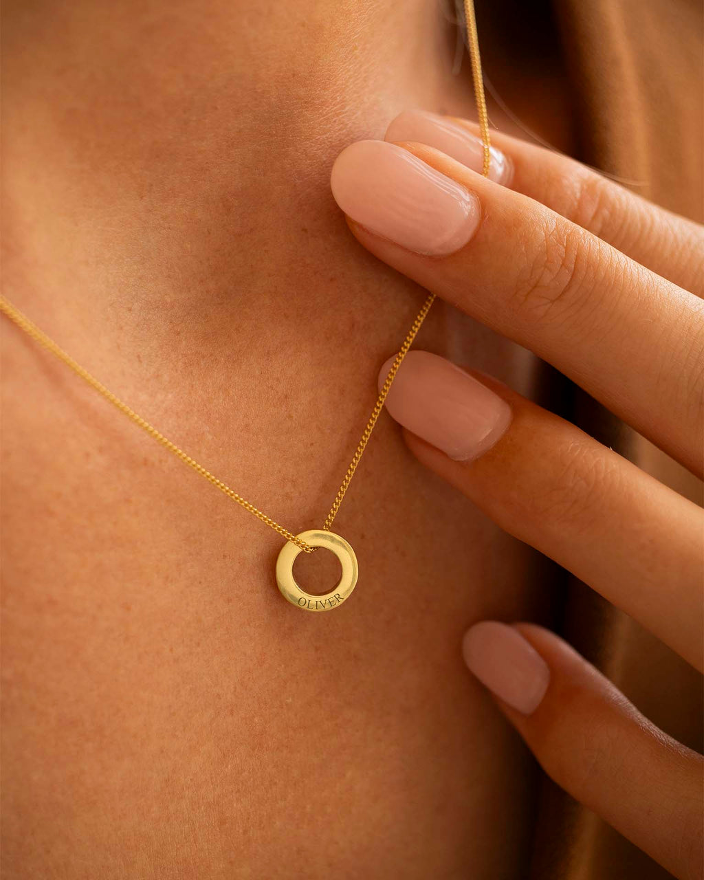 Gold necklace with a circular pendant worn by a person