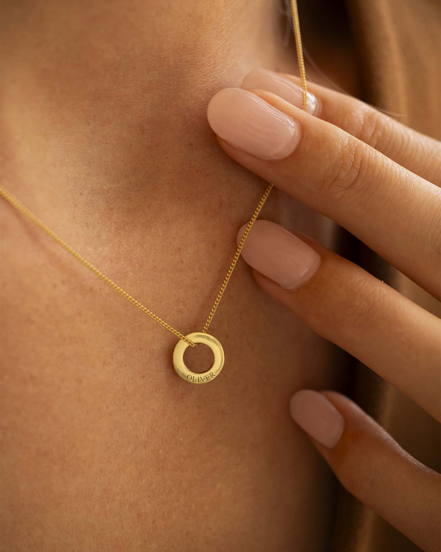 Gold necklace with a circular pendant worn by a person