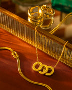 Gold necklace with circular pendants on a reflective surface