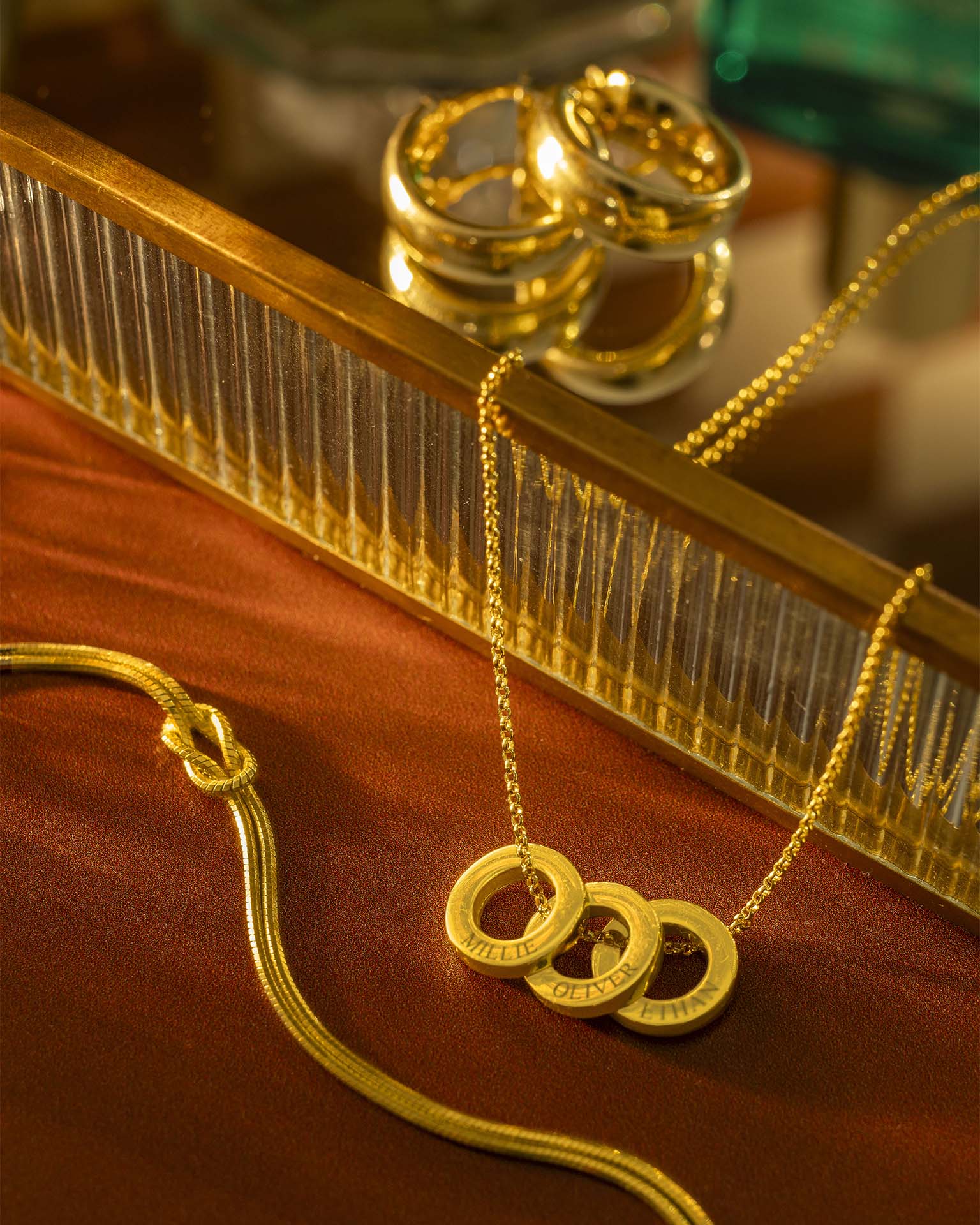 Gold necklace with circular pendants on a reflective surface