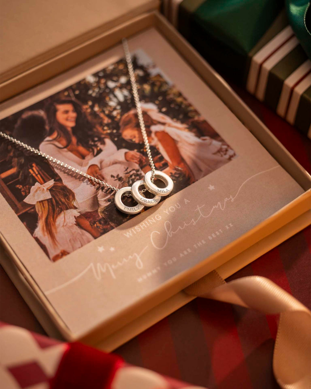 Silver necklace with interlocking rings on a Christmas card inside an open box.
