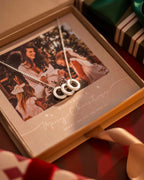 Silver necklace with interlocking rings on a Christmas card inside an open box.