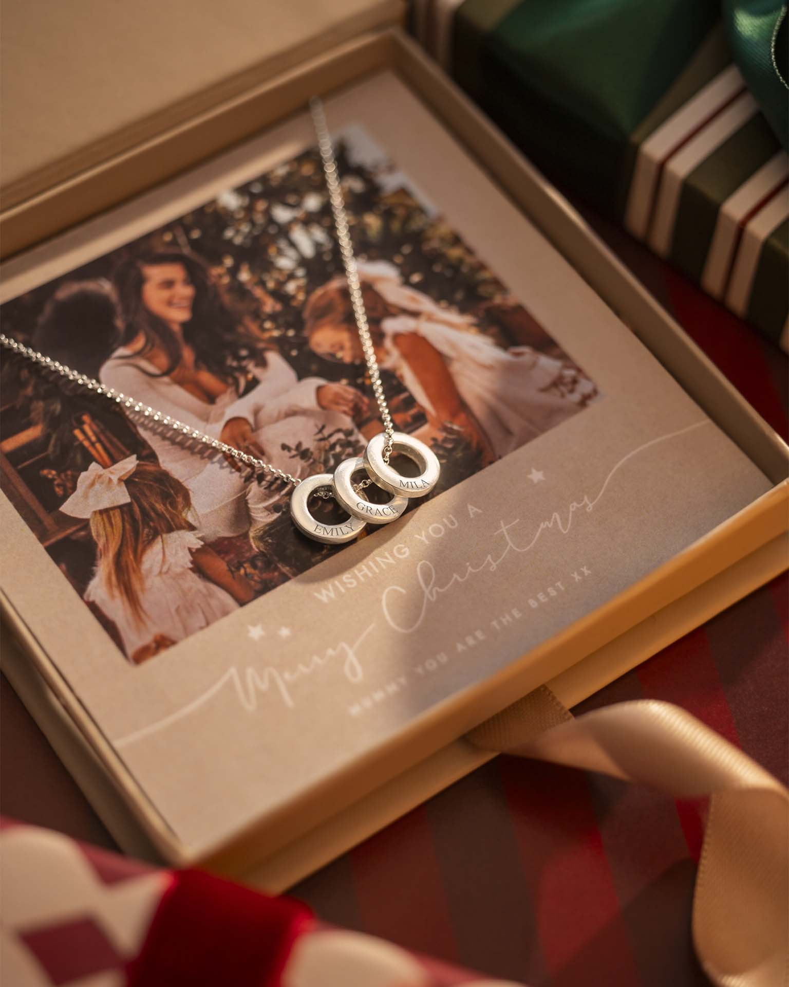 Silver necklace with interlocking rings on a Christmas card inside an open box.