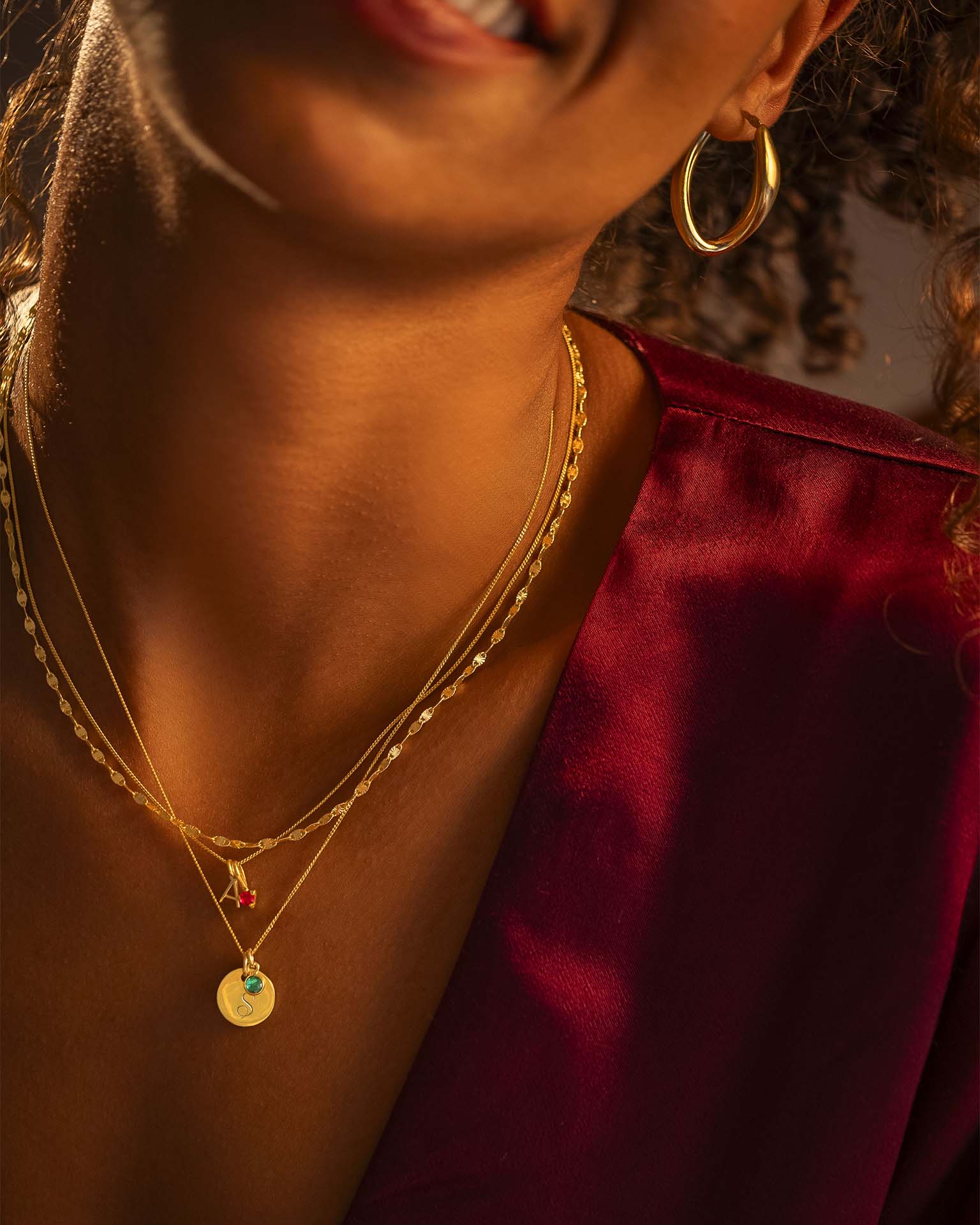 Close-up of a person wearing gold necklaces and earrings with a blurred background
