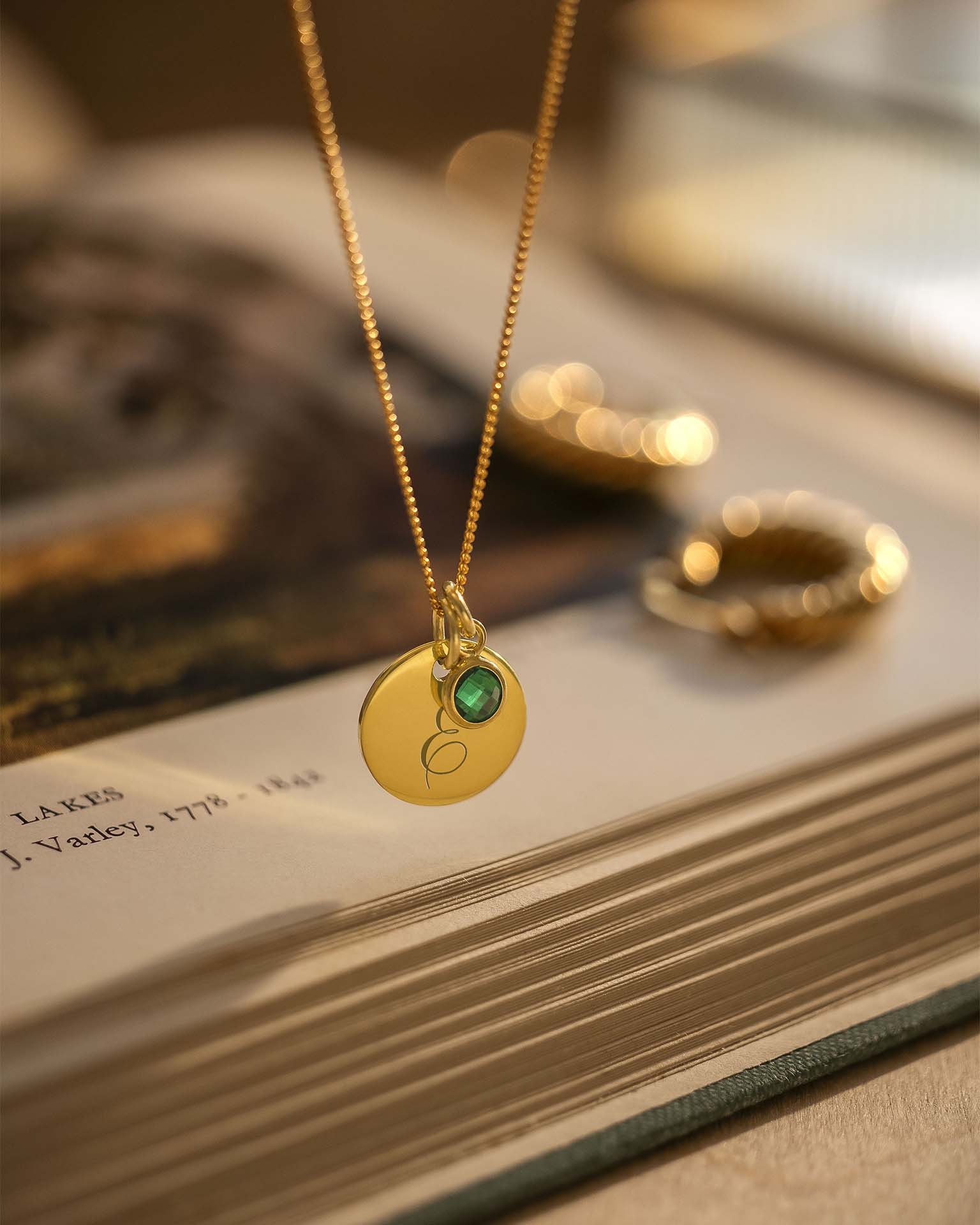 Gold necklace with a green gemstone pendant on a book