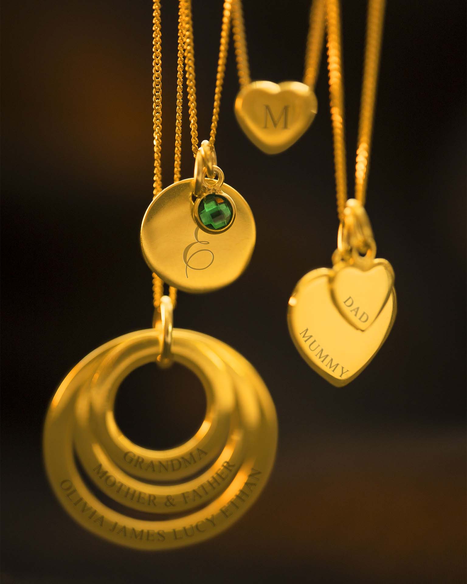 Gold necklaces with engraved pendants on a dark background