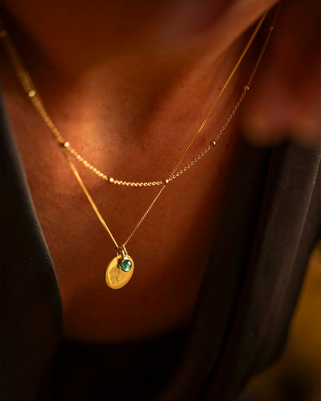 Gold necklace with a green gemstone pendant on a blurred background