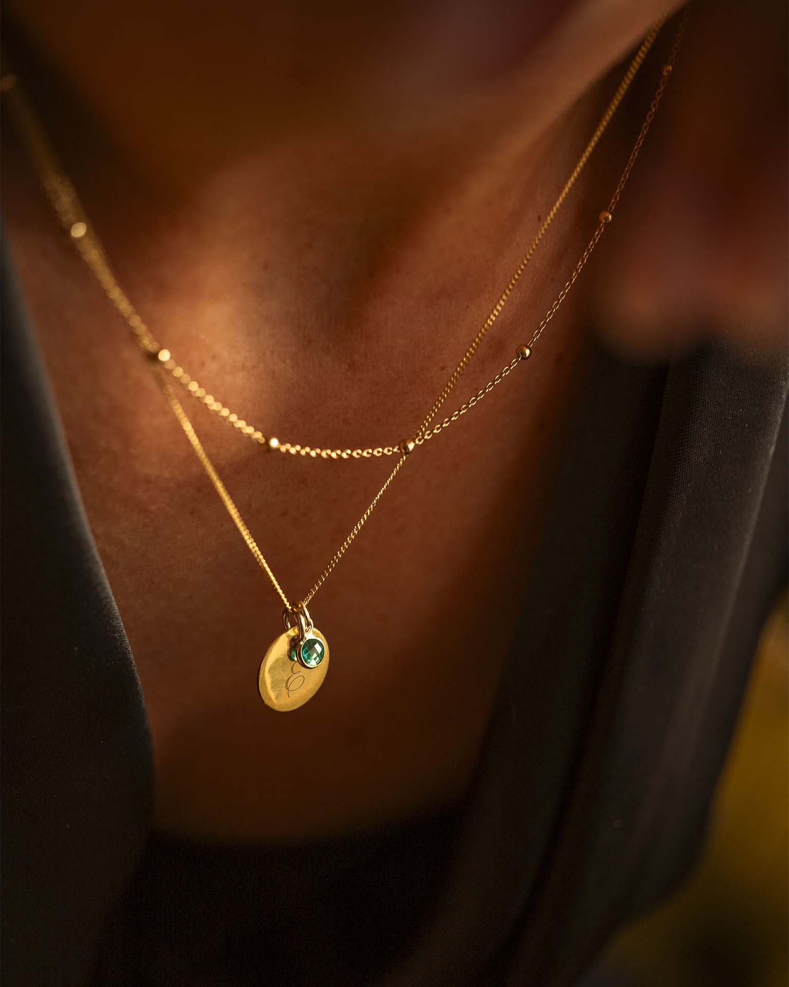 Gold necklace with a green gemstone pendant on a blurred background