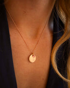 Gold necklace with a pendant on a person's neck against a dark background