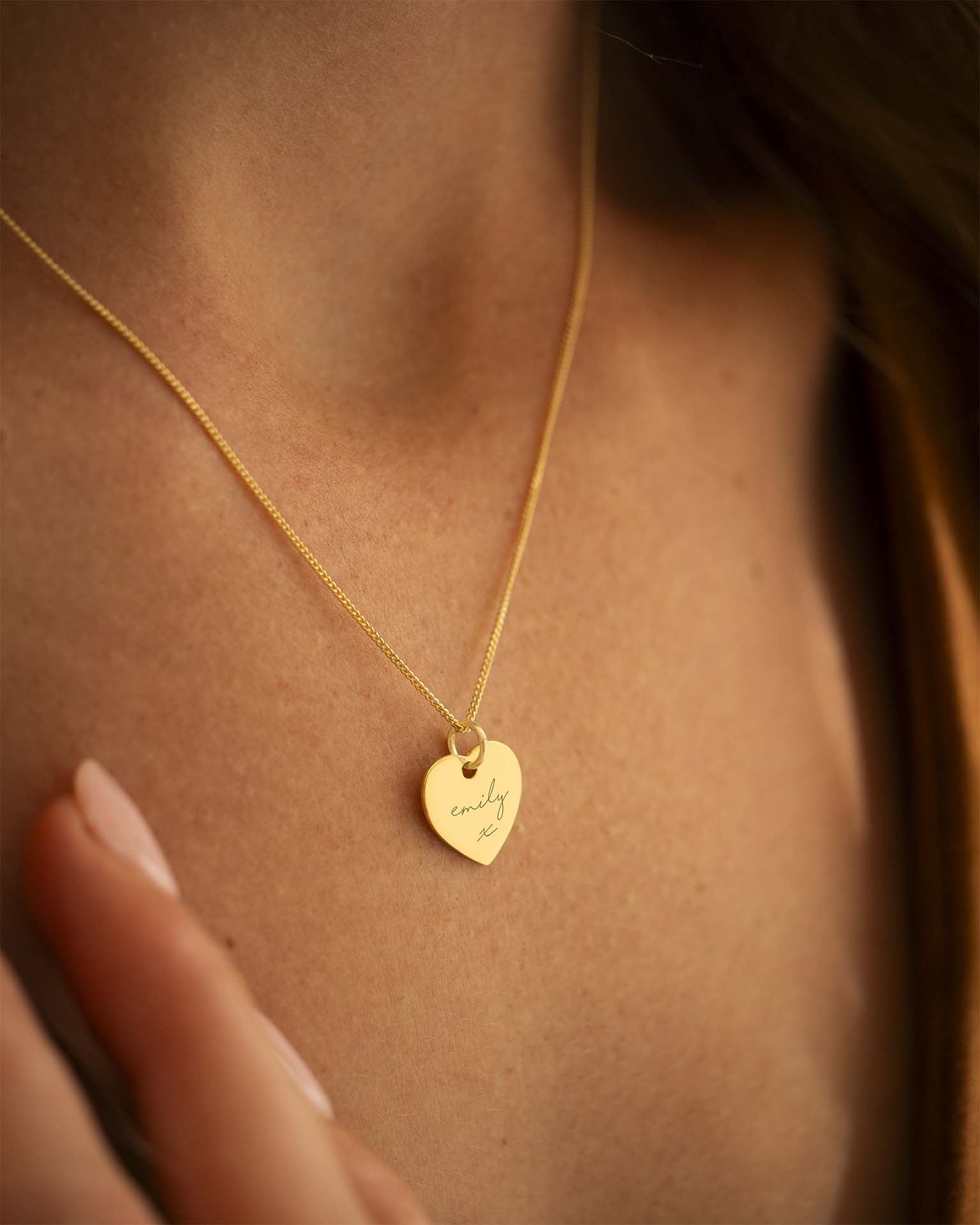 Gold necklace with a heart-shaped pendant on a person's neck. | Christmas