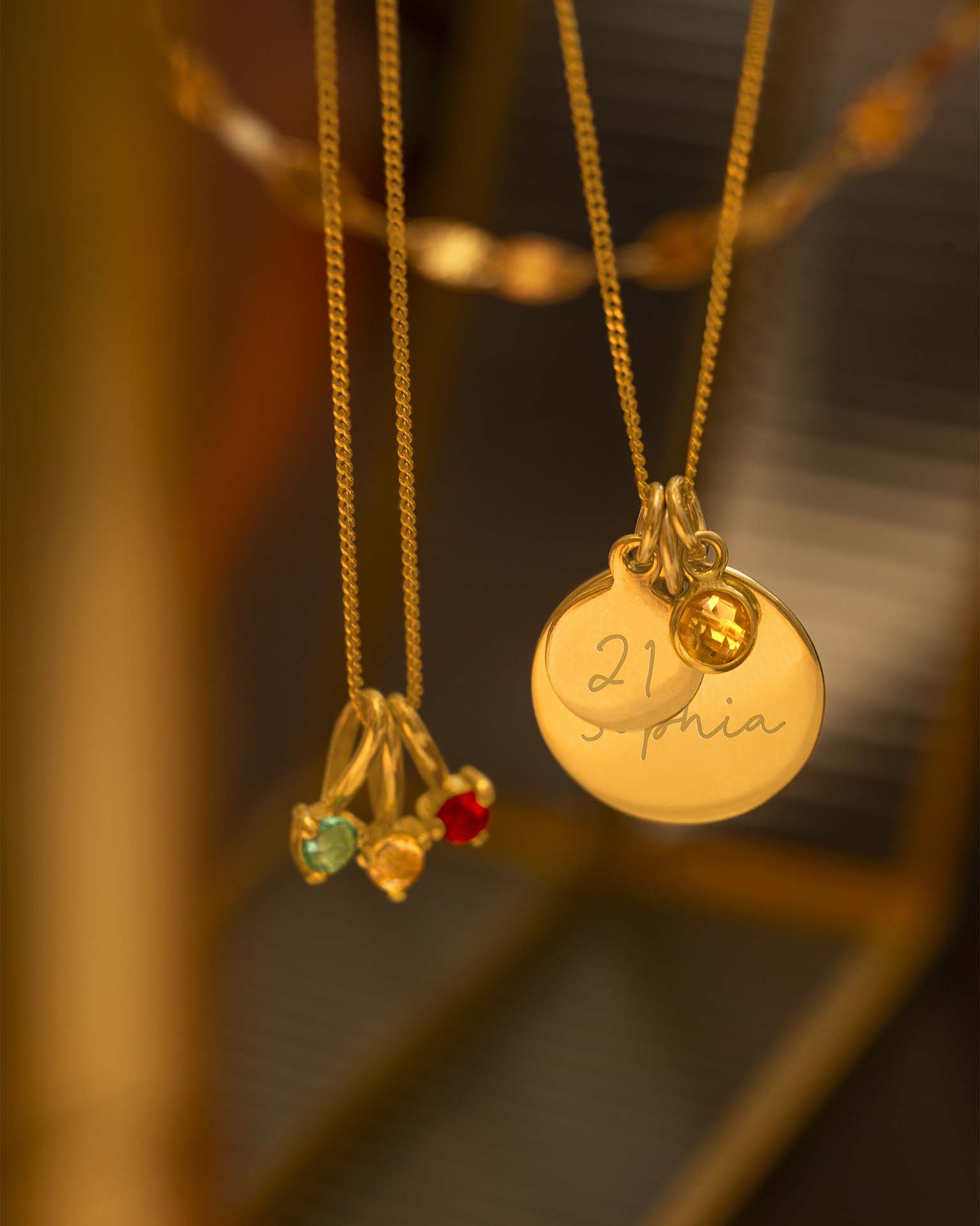 Two gold necklaces with pendants on a blurred background