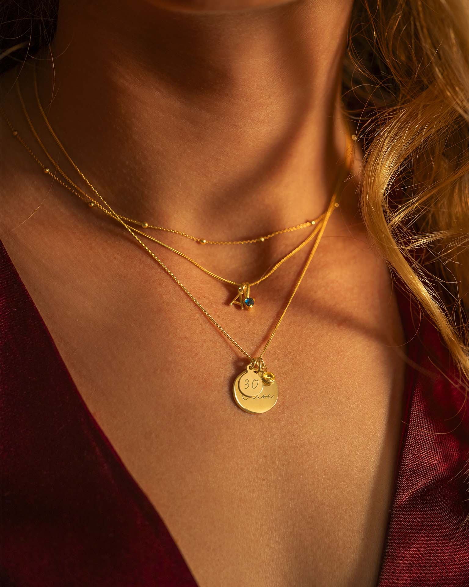 Close-up of a person wearing multiple gold necklaces with pendants.
