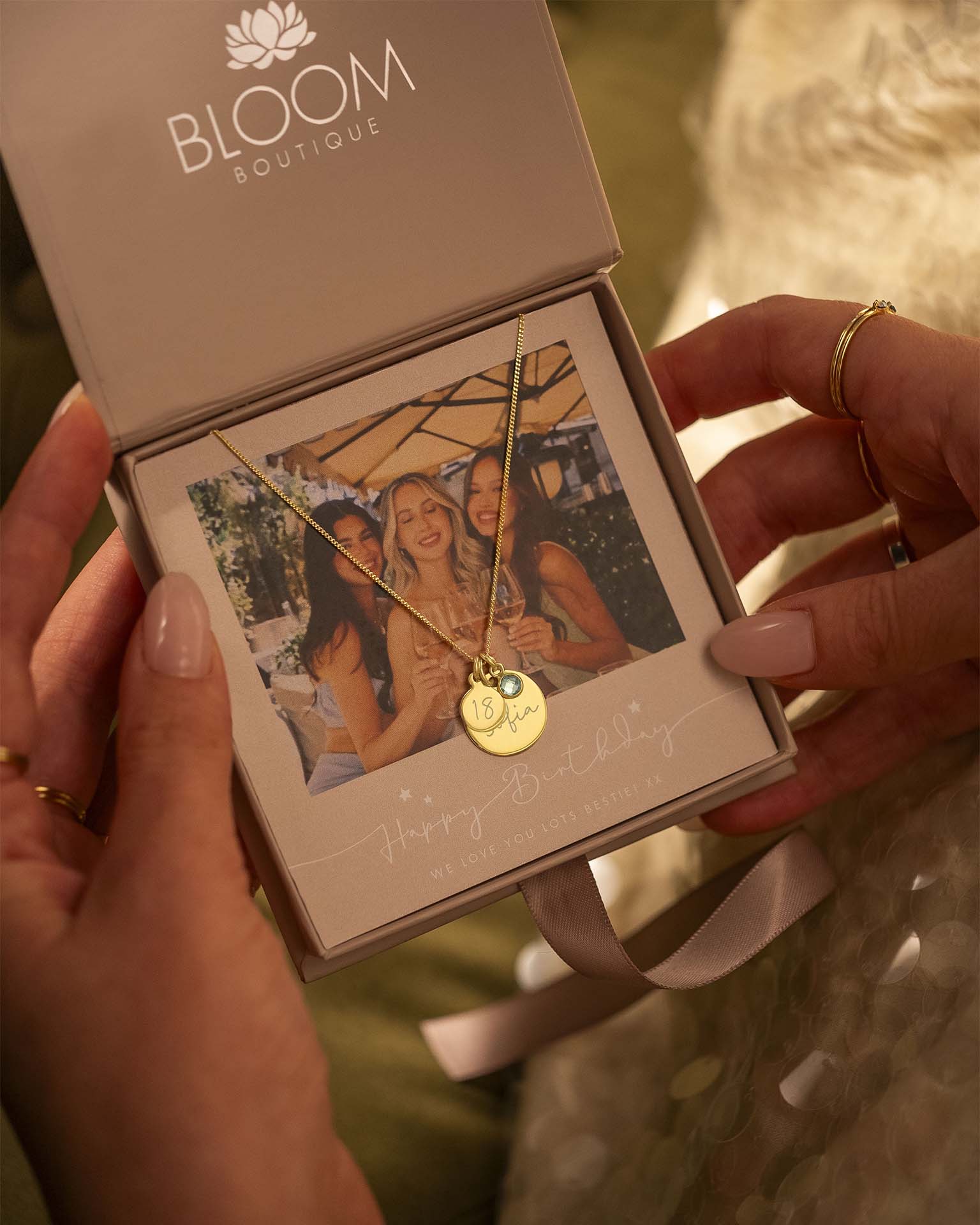 Gold necklace with a pendant held in a 'Bloom Boutique' box.
