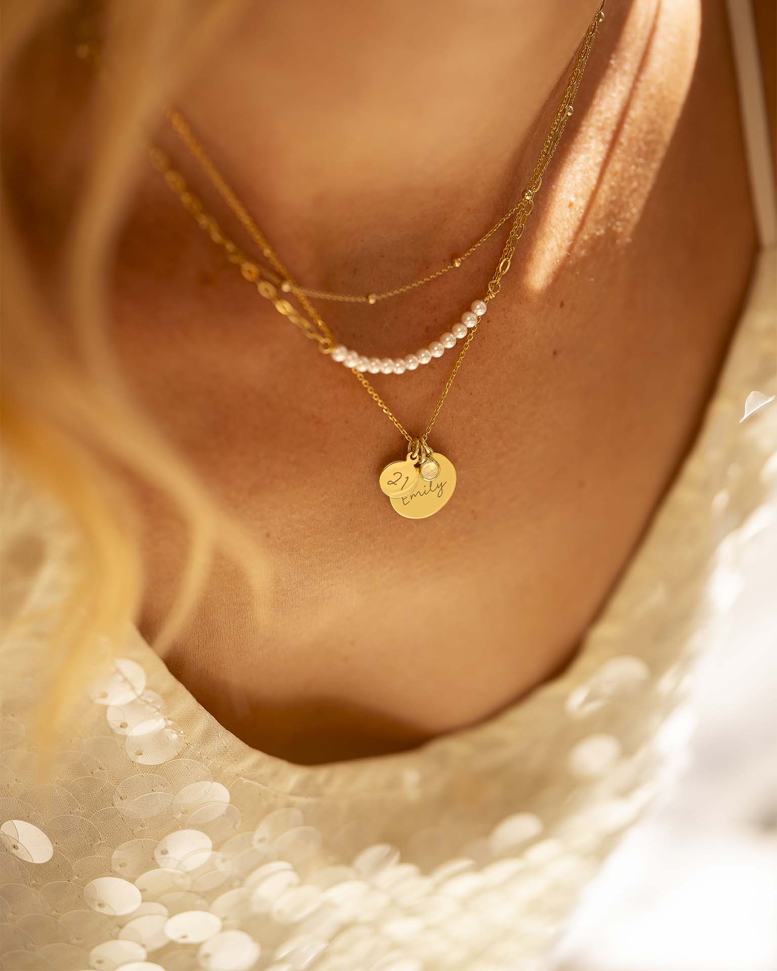 Close-up of a person wearing multiple necklaces with a soft focus background