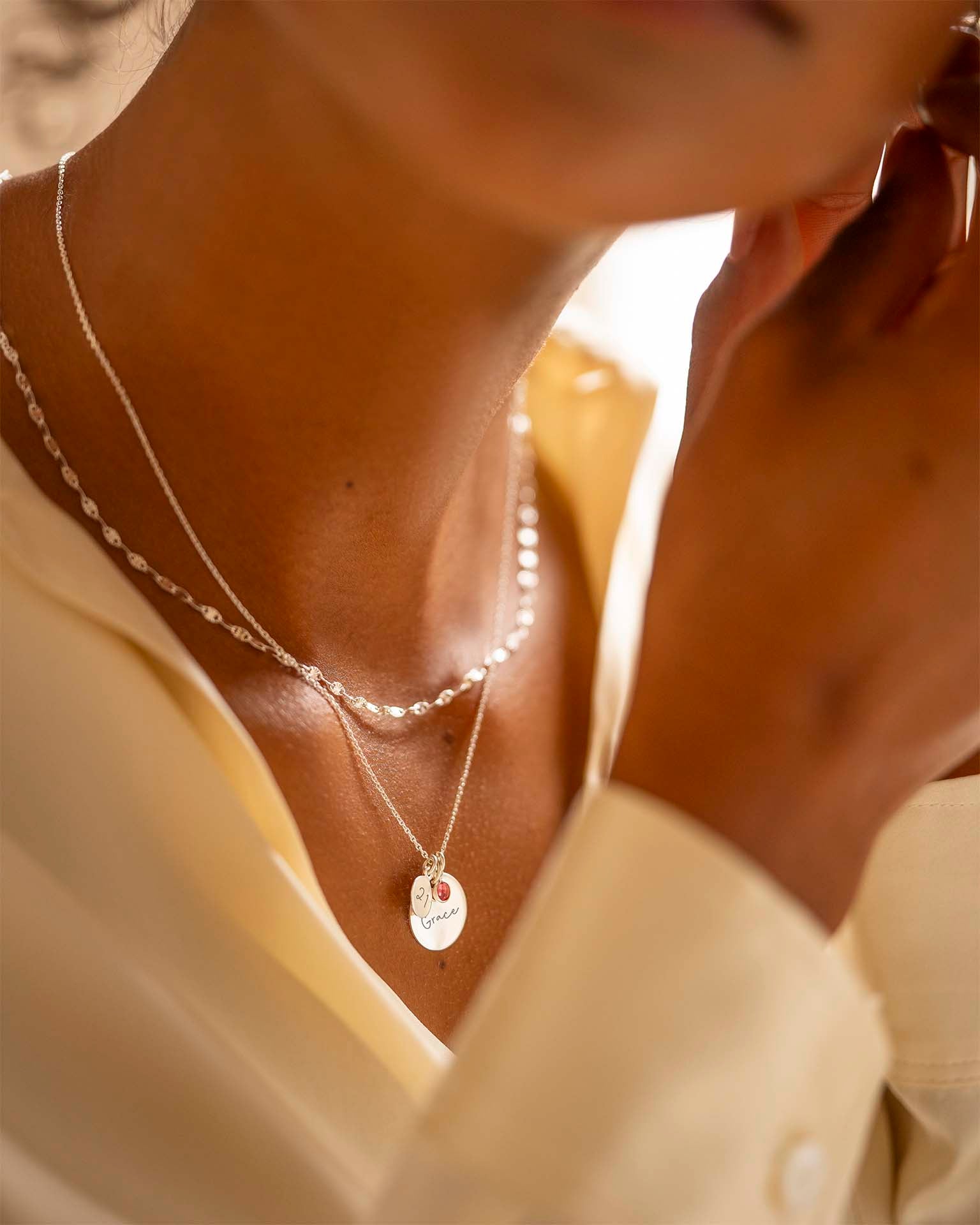 Close-up of a person wearing a delicate necklace with a pendant.