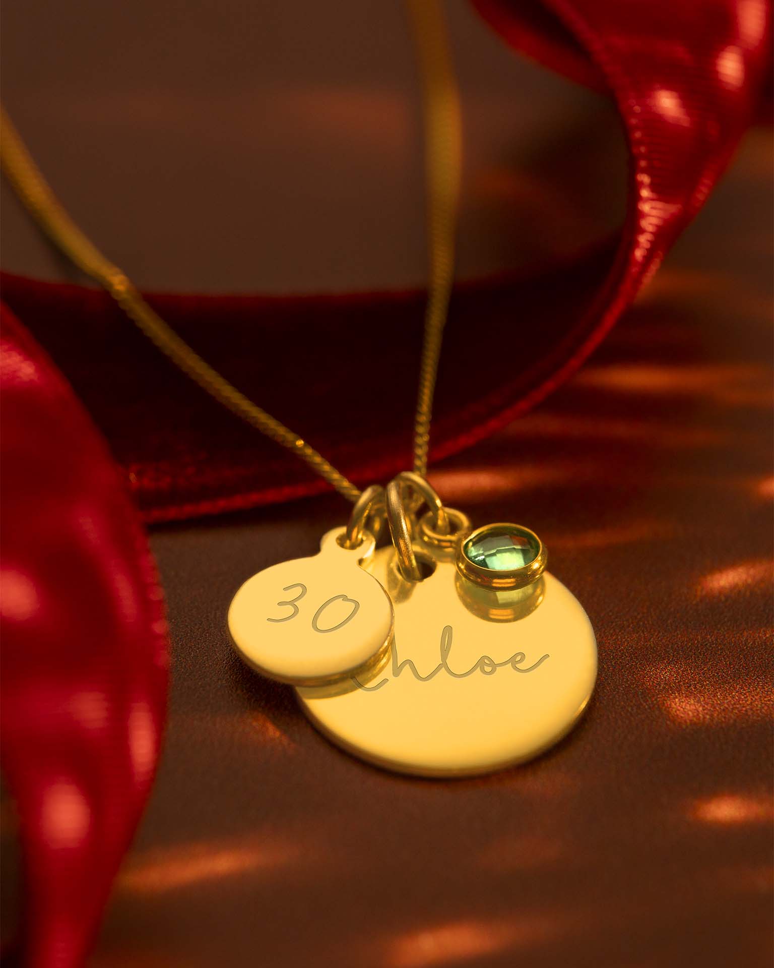 Gold necklace on red background with ribbon behind. | Christmas