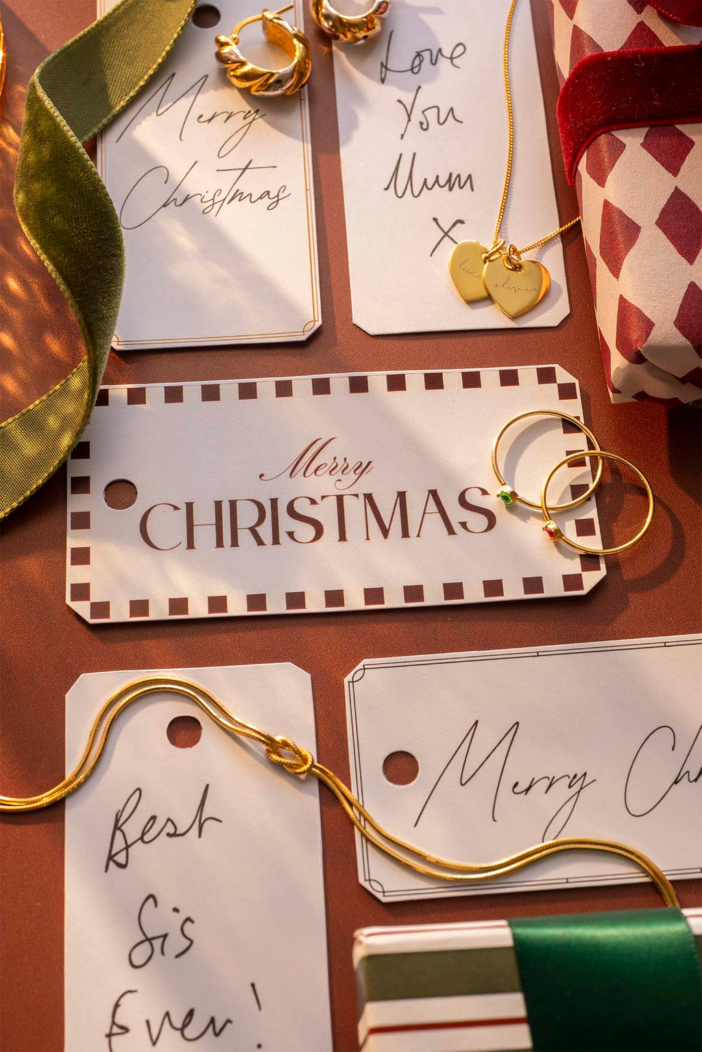 Gold earrings on Christmas-themed gift tags with decorative ribbons.