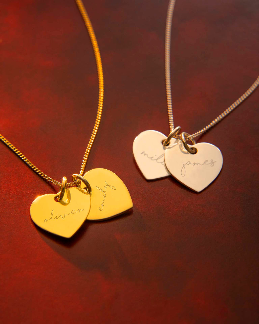 Two gold necklaces with heart-shaped pendants on a dark red background | Christmas