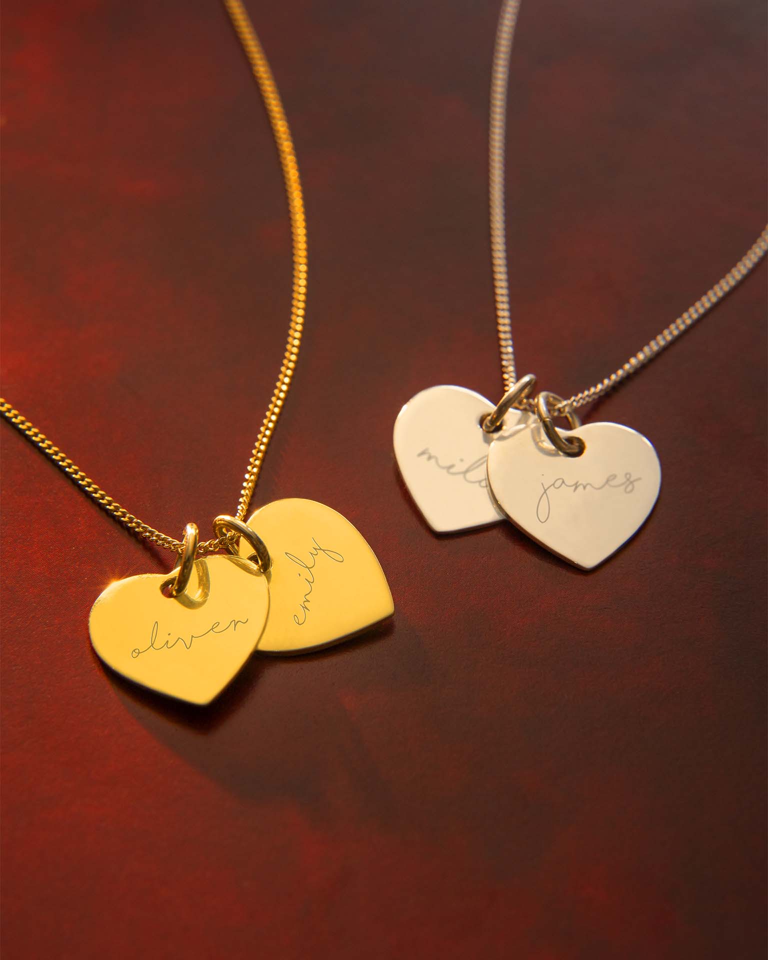 Two gold necklaces with heart-shaped pendants on a dark red background | Christmas