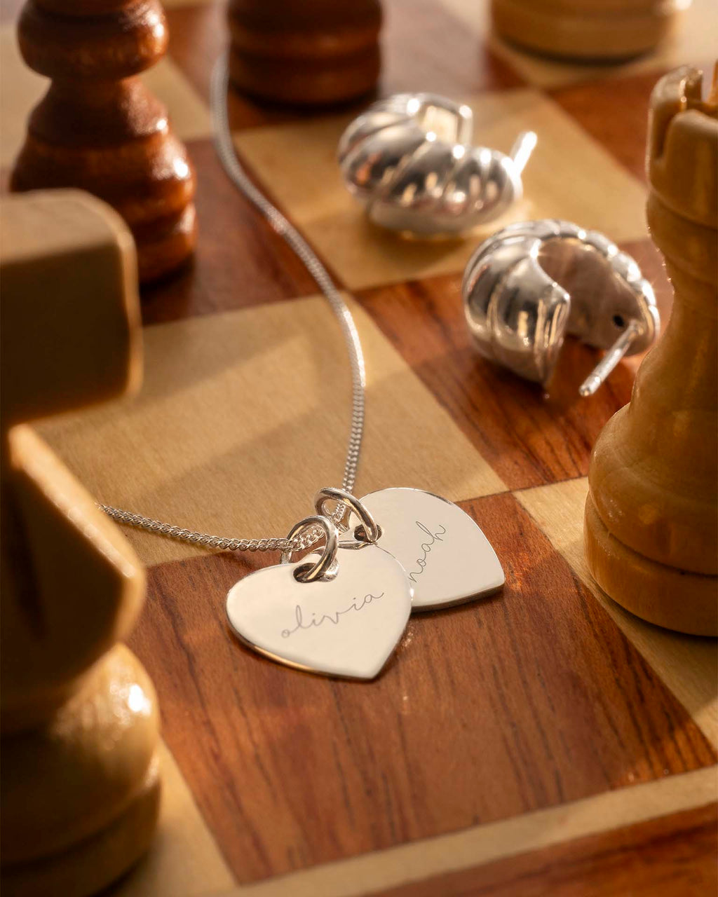 Silver necklace with heart-shaped pendants on a chessboard