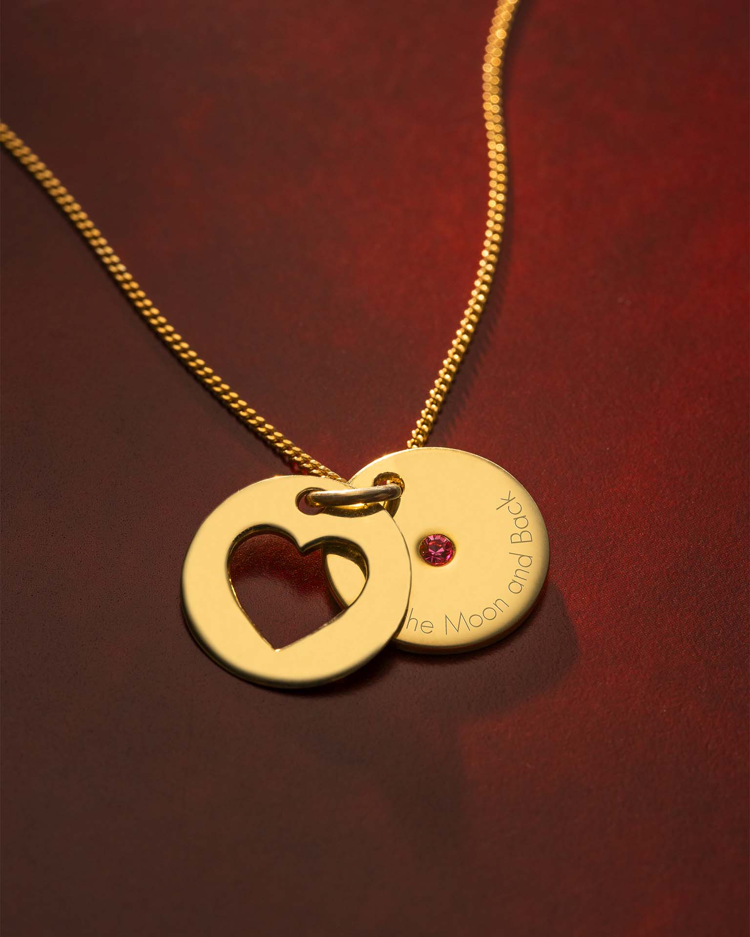 Gold necklace with heart-shaped pendant on a red background | Christmas