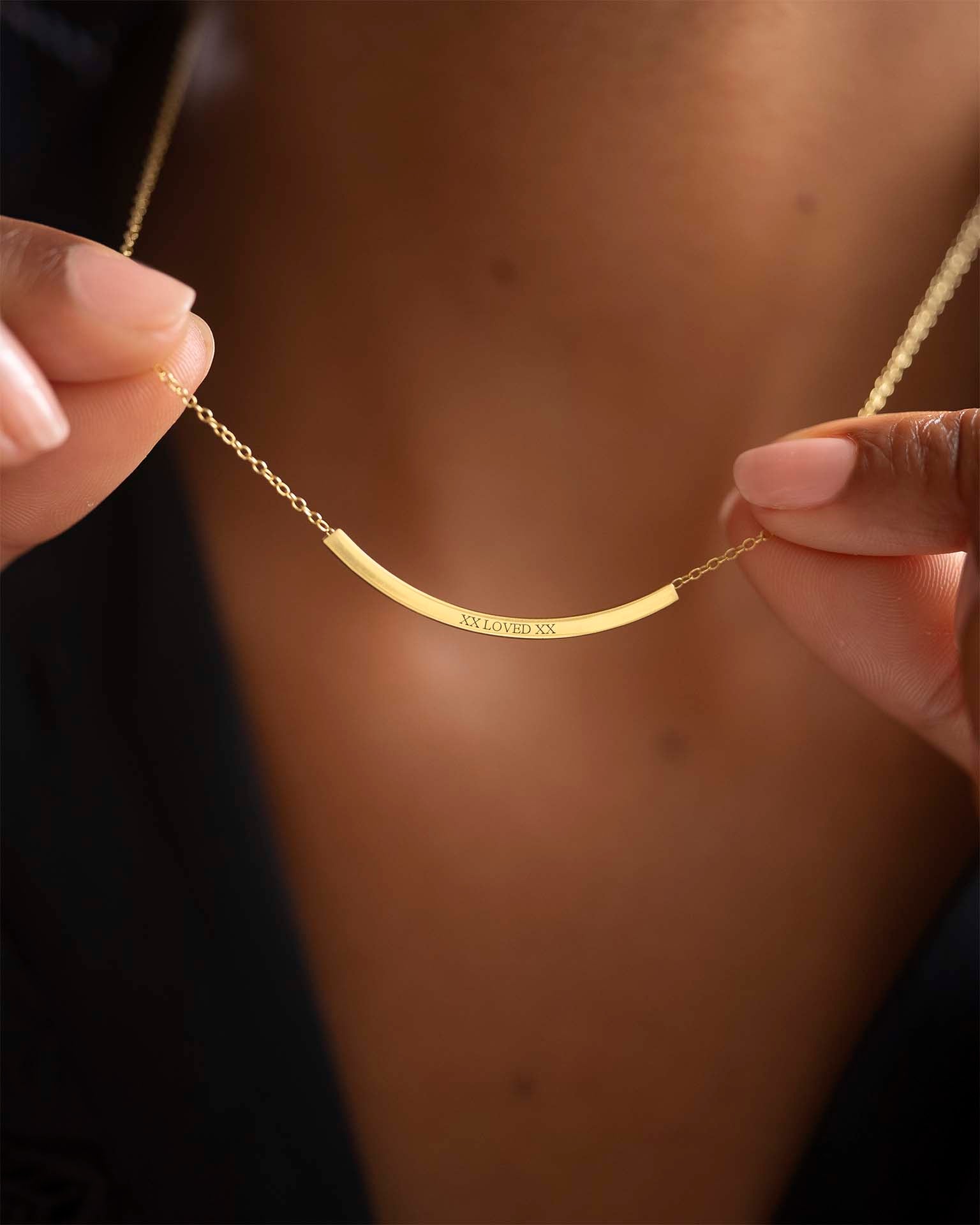 Gold necklace held by hands with a blurred background | Christmas