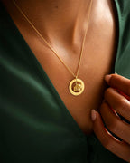 Gold necklace with a pendant on a person wearing a green top. | Christmas