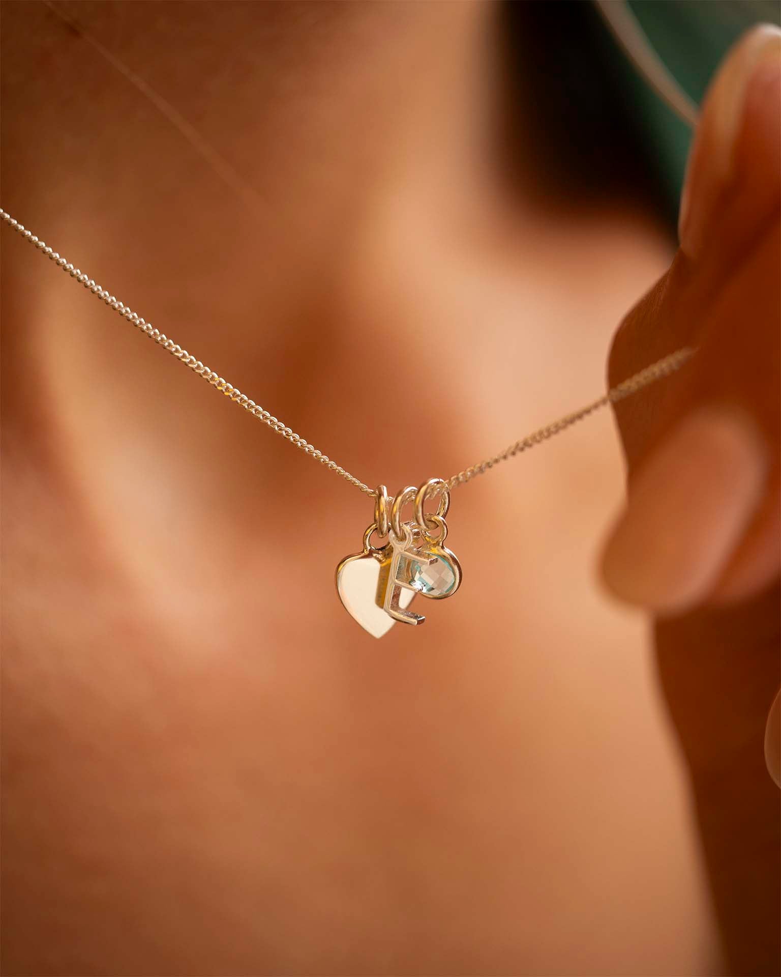 Necklace with heart and moon charm held by a hand against a blurred background | Christmas
