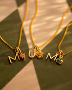 Three gold necklaces with charms on a textured surface