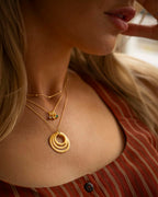 Close-up of a woman wearing gold necklaces with a blurred background