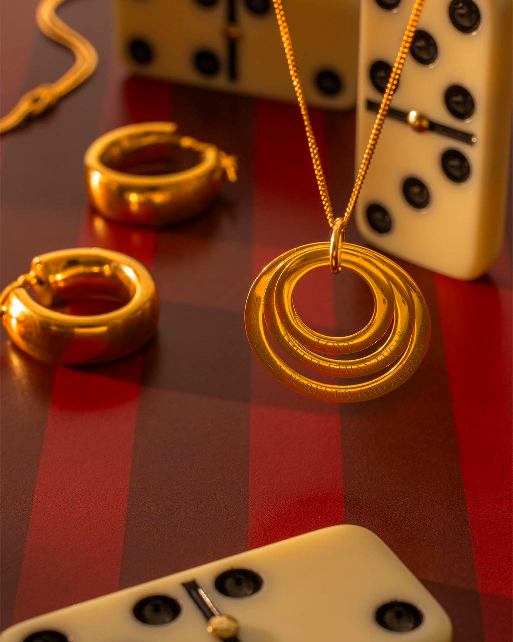 Gold necklace and earrings on a checkered surface with dice in the background 