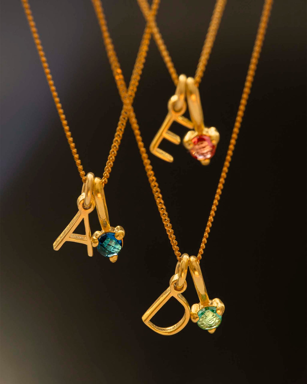 Three gold necklaces with gemstone pendants on a dark background | Christmas