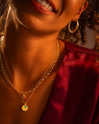 Close-up of a person wearing gold jewelry with a blurred background
