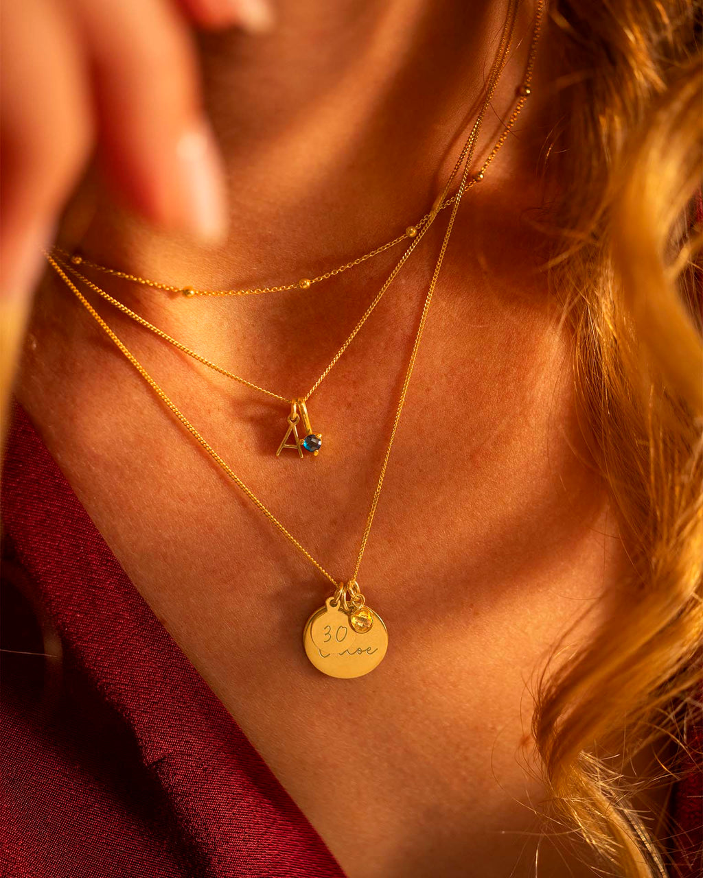 Close-up of a person wearing multiple gold necklaces with visible pendants.