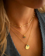 Close-up of a person wearing gold necklaces with pendants.