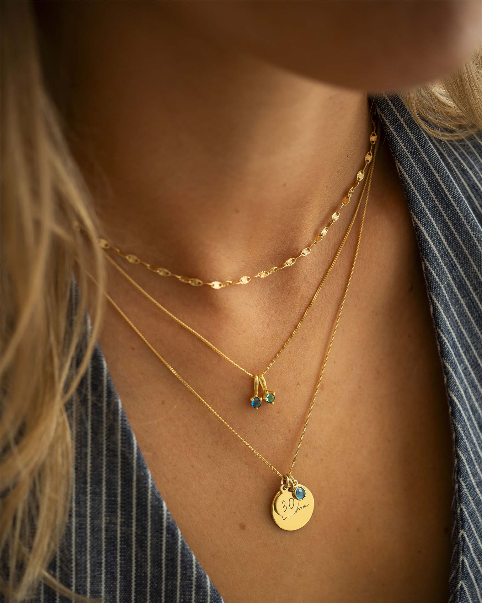 Close-up of a person wearing gold necklaces with pendants.