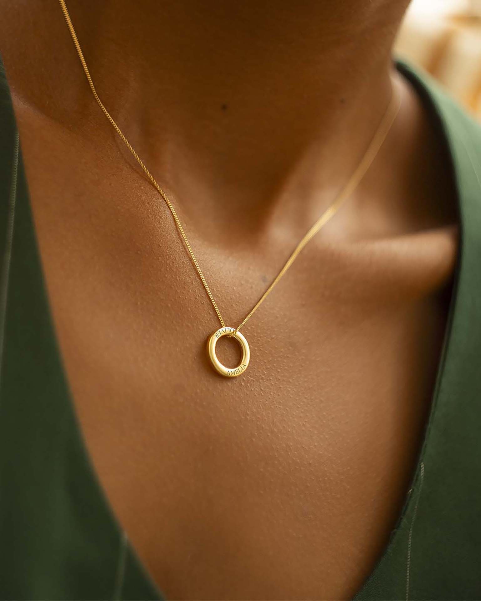 Gold necklace on model with green top. | Christmas