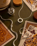 Silver jewelry on playing cards with a bottle of Cognac in the background