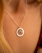 Necklace with a circular pendant featuring heart charms on a person's neck. | Christmas