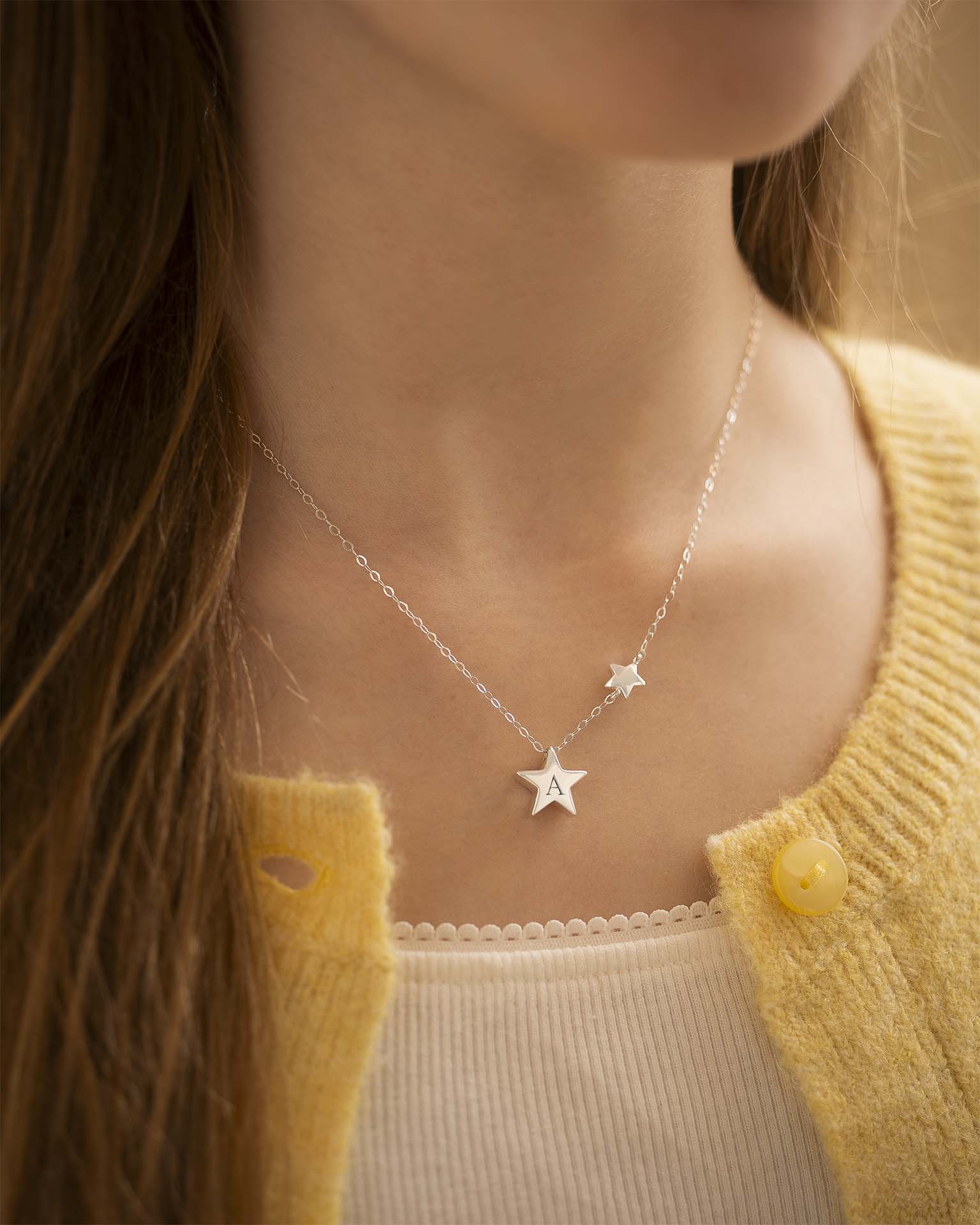 Star-shaped necklace worn by a person with a yellow cardigan | Christmas