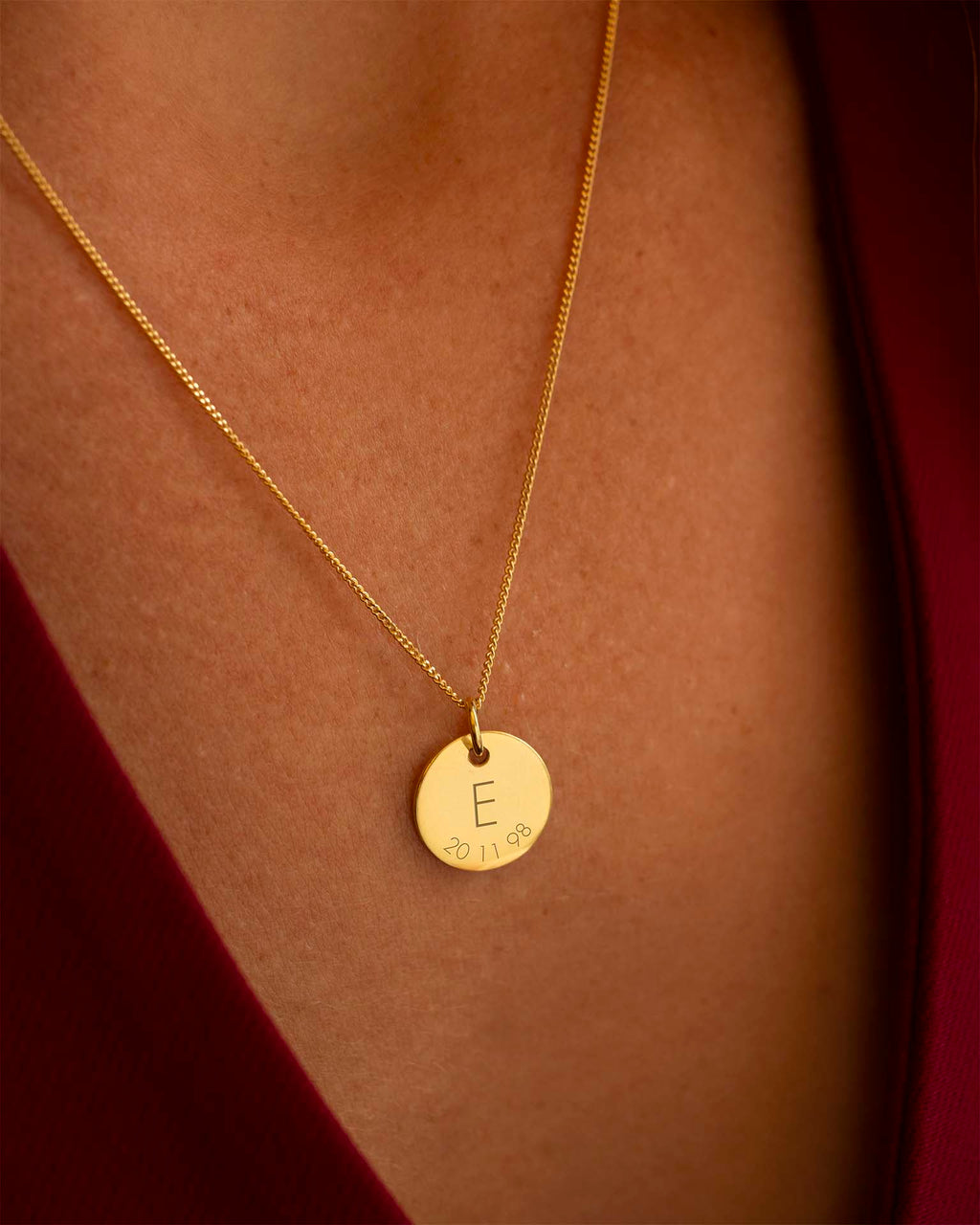 Gold necklace with a round pendant featuring the letter 'E' on a person's neck. | Christmas