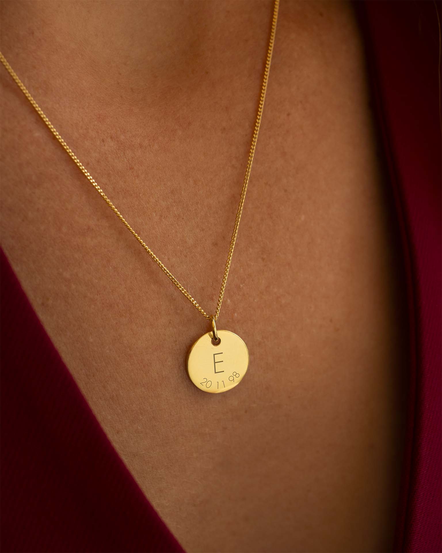Gold necklace with a round pendant featuring the letter 'E' on a person's neck. | Christmas
