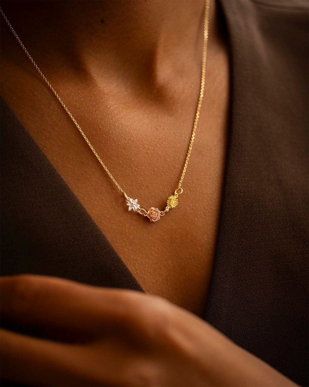 Gold necklace with star and rose pendant on a person wearing a brown garment. | Christmas